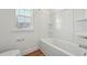 Bright bathroom featuring a tub and shower combination, white tile surround, window and wood flooring at 88 Antler Steel Dr, Clayton, NC 27527
