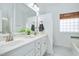 Well-lit bathroom with double sinks, white cabinets, tile flooring and glass block window for natural light at 104 Spooner Ct, Holly Springs, NC 27540