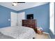 Comfortable bedroom has blue walls, carpet, and television on a dresser with closet and window at 104 Spooner Ct, Holly Springs, NC 27540