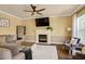 Comfortable living room with a fireplace, ceiling fan, plush seating, and lots of natural light at 104 Spooner Ct, Holly Springs, NC 27540