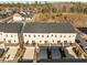 Rear aerial view of tan townhomes showcasing decks and driveways leading to garages below at 1414 Excelsior Grand Ave, Durham, NC 27713