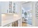 Modern wet bar with sleek white cabinets, stone countertops, a beverage fridge, and herringbone backsplash at 240 Seaforth Landing Dr, Pittsboro, NC 27312
