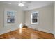 A serene bedroom featuring beautiful hardwood floors and two sunlit windows with a view of the outdoors at 2504 E East Geer St, Durham, NC 27704