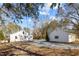 An exterior shot of a white home with a gravel driveway in a wooded location on a sunny day at 2504 E East Geer St, Durham, NC 27704