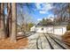 An exterior shot of a white home with a detached garage, gravel driveway, and mature trees at 2504 E East Geer St, Durham, NC 27704