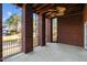 Covered back porch with brick columns and ceiling fan overlooking a pond and wooded area at 2600 Buckingham Dr, Sanford, NC 27330