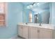 Bright bathroom with a large mirror over a double sink vanity and blue walls at 4009 Brittabby Ct, Raleigh, NC 27606