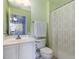 A well-lit bathroom featuring a single sink, white cabinets, and a shower/tub with a curtain at 4009 Brittabby Ct, Raleigh, NC 27606