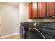 Functional laundry room with washer, dryer, and built-in dark wood cabinets for additional storage at 4009 Brittabby Ct, Raleigh, NC 27606