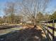 A long driveway lined with a wooden fence leads to barns surrounded by trees on the property at 4063 Nc-39, Selma, NC 27576