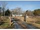A long gravel driveway leads to a home with a white exterior, front porch, and mature trees at 4063 Nc-39, Selma, NC 27576