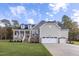 Beautiful home featuring a stone facade, a charming front porch, and a three-car garage on a well-manicured lawn at 409 Grading Stick Ct, Angier, NC 27501