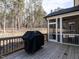 Back deck featuring a black grill and screened-in porch with views of the surrounding forest at 696 The Parks Dr, Pittsboro, NC 27312