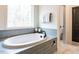 Bright bathroom highlighting a soaking tub with tiled surround, large window, and towel rack at 696 The Parks Dr, Pittsboro, NC 27312