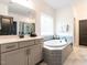 Bathroom boasting a soaking tub with tiled surround, vanity with sink, and a window at 696 The Parks Dr, Pittsboro, NC 27312