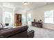 Bright living room featuring a brown leather couch, gun cabinet, and media console with lots of natural light at 696 The Parks Dr, Pittsboro, NC 27312