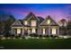Beautifully lit two-story home with manicured lawn, stone accents, and inviting front porch at dusk at 1100 Kingwood Dr, Raleigh, NC 27609