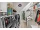 Functional laundry room with modern washer and dryer units, storage shelves, and a utility sink at 1100 Kingwood Dr, Raleigh, NC 27609