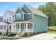 An angled view of a blue two-story home showcasing its well-maintained lawn and modern architectural design at 120 Weavers Grove Dr, Chapel Hill, NC 27514