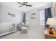 Neutral bedroom featuring a crib, chair, ottoman, ceiling fan, two windows at 140 Big Barn Dr, Wendell, NC 27591