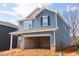 Two-story blue home featuring an unfinished two-car garage, brick foundation and gray home to the left at 2019 Cherry Creek Rd, Haw River, NC 27258