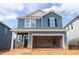 Two-story blue home featuring an unfinished two-car garage and a light brick foundation at 2019 Cherry Creek Rd, Haw River, NC 27258