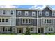 New construction townhome featuring gray siding, brick accents, and a well-manicured lawn under a clear blue sky at 2241 Horton Park Dr, Apex, NC 27539