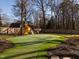 Backyard with a playset, lush green lawn, and mature trees, perfect for Gathering fun and outdoor activities at 2511 Pineway Dr, Burlington, NC 27215