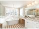 Bright bathroom with a freestanding tub beneath shuttered windows, and a vanity with stone countertop and elegant chandelier at 2511 Pineway Dr, Burlington, NC 27215
