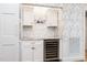 Charming butler's pantry with white cabinetry, a wine cooler, decorative tile backsplash, and stylish wallpaper at 2511 Pineway Dr, Burlington, NC 27215