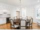 Bright dining room with a round wooden table, decorative wallpaper, modern chandelier, and a butler's pantry at 2511 Pineway Dr, Burlington, NC 27215