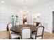 Bright dining room with a round wooden table, decorative wallpaper, modern chandelier, and a light aqua china cabinet at 2511 Pineway Dr, Burlington, NC 27215