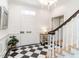 Bright foyer featuring a checkered tile floor, paneled walls, a staircase, and decorative accents at 2511 Pineway Dr, Burlington, NC 27215