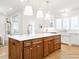 Bright kitchen featuring a large island with bar seating and wooden cabinetry with a built-in stainless sink at 2511 Pineway Dr, Burlington, NC 27215
