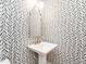 Stylish powder room featuring a pedestal sink, gold fixtures, and eye-catching black and white patterned wallpaper at 2511 Pineway Dr, Burlington, NC 27215