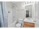 Bathroom with shower over tub with blue curtain, toilet, and oak vanity at 3349 Tarleton W, Durham, NC 27713
