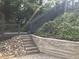 View of backyard with retaining wall, stairs leading up to deck and gray railings at 3412 Rock Creek Dr, Raleigh, NC 27609