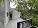View of gray stained wooden deck and siding, string lights, and door to house surrounded by trees at 3412 Rock Creek Dr, Raleigh, NC 27609
