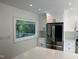 Well-lit kitchen with stainless steel refrigerator, white cabinets and countertops, and a window overlooking the outdoor scenery at 3412 Rock Creek Dr, Raleigh, NC 27609