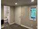 View of room with wood paneled walls, vinyl floors, a window, and adjacent bathroom at 3412 Rock Creek Dr, Raleigh, NC 27609