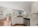 Modern kitchen area featuring white cabinets, stainless steel dishwasher, and an open view into a cozy living space at 3515 Meadowrun Dr, Durham, NC 27707