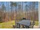 Outdoor patio with a grill and iron table surrounded by the beauty of nature at 4555 Sugarbend Way, Raleigh, NC 27606