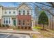 Charming two-story townhome featuring brick accents, a well-manicured lawn, and a welcoming green front door at 4555 Sugarbend Way, Raleigh, NC 27606