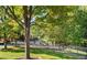 A playground sits on a grassy area next to mature trees and a parking area, perfect for families to enjoy at 4555 Sugarbend Way, Raleigh, NC 27606