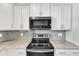 Close-up of modern stove and microwave with stainless steel appliances and granite countertops at 507 Gateway Townes Blvd, Wake Forest, NC 27587
