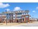Charming row of townhouses with varied facades and manicured lawns, set against a backdrop of blue skies and puffy clouds at 507 Gateway Townes Blvd, Wake Forest, NC 27587