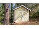 Shed with white trim and cream siding, surrounded by mature trees at 6404 Dixon Dr, Raleigh, NC 27609