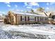 Well-maintained brick home with covered side entrance, black shutters, and snowy yard at 7103 Big Horn Dr, Hillsborough, NC 27278