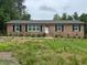 Charming brick home featuring a white door, black shutters, and a well-manicured front yard at 7103 Big Horn Dr, Hillsborough, NC 27278