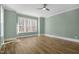 Large bedroom with hardwood floors, light green walls, expansive windows, and modern ceiling fan at 7112 Camp Side Ct, Raleigh, NC 27613